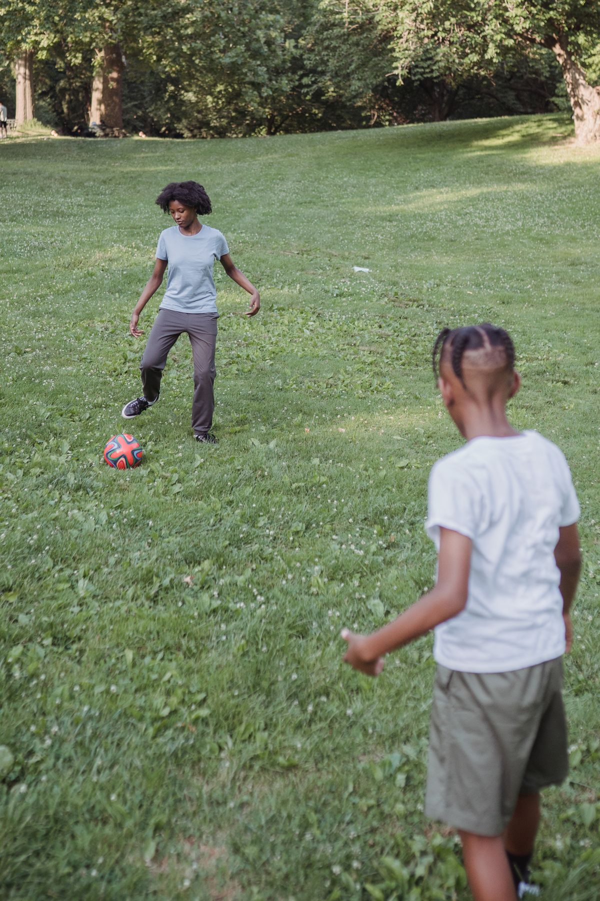 Parent and child playing football together in a park